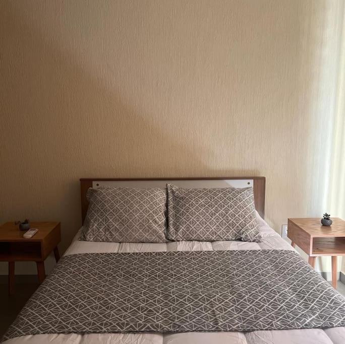 een bed in een slaapkamer met 2 nachtkastjes en 2 tafels bij Hermosa casa, sur de Guadalajara in Guadalajara