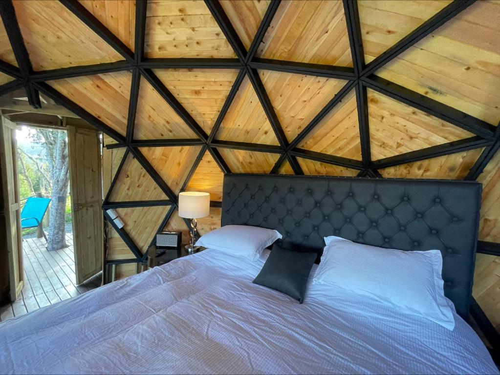 Cama en habitación con techo de madera en Entre-pinos Glamping WiFi Vista 360º, en Guarne