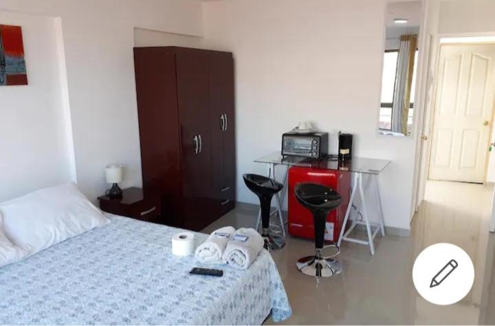 a bedroom with a bed and a table with a microwave at wilsonpedro in Iquique