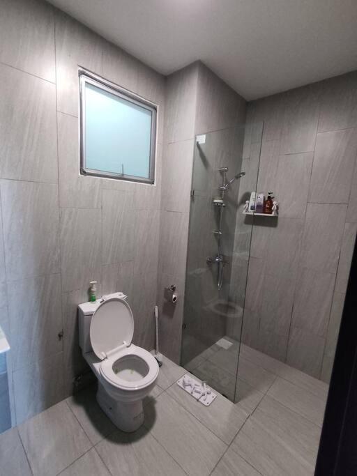 baño con aseo y ducha con ventana en Near Kuching Airport Liberty Grove Apartment, en Kuching