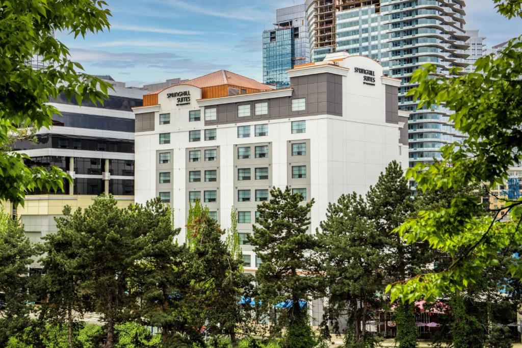 un bâtiment blanc avec des arbres devant de grands bâtiments dans l'établissement SpringHill Suites Seattle Downtown, à Seattle