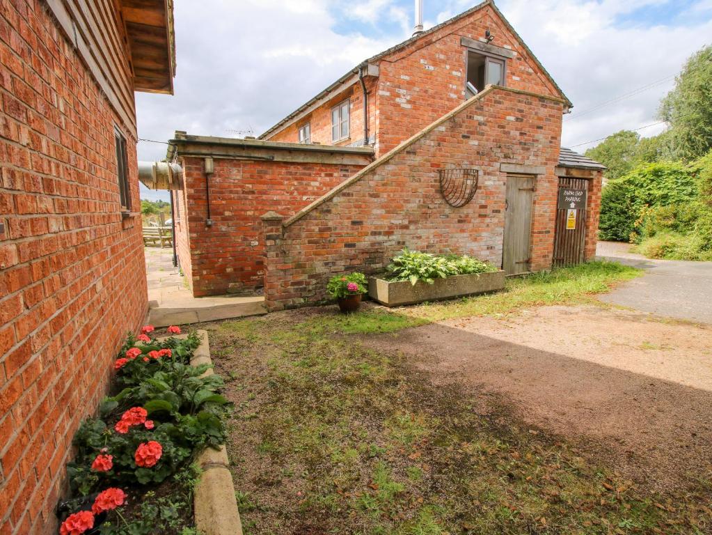 an old brick building with flowers in the yard at The Barn in Preesgreen