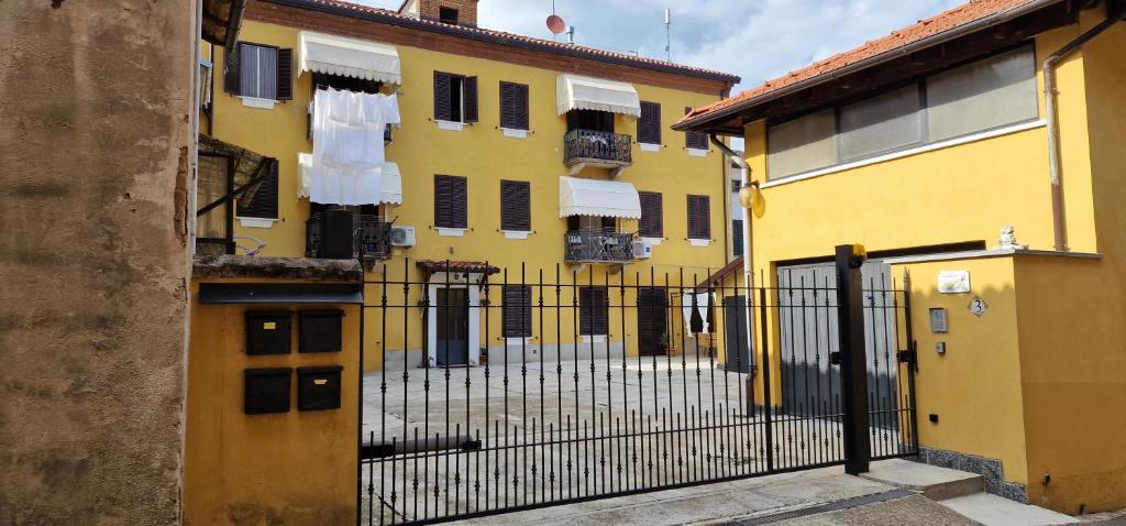 een geel gebouw met een hek ervoor bij Casa soggiorno il Quetzales in Valenza