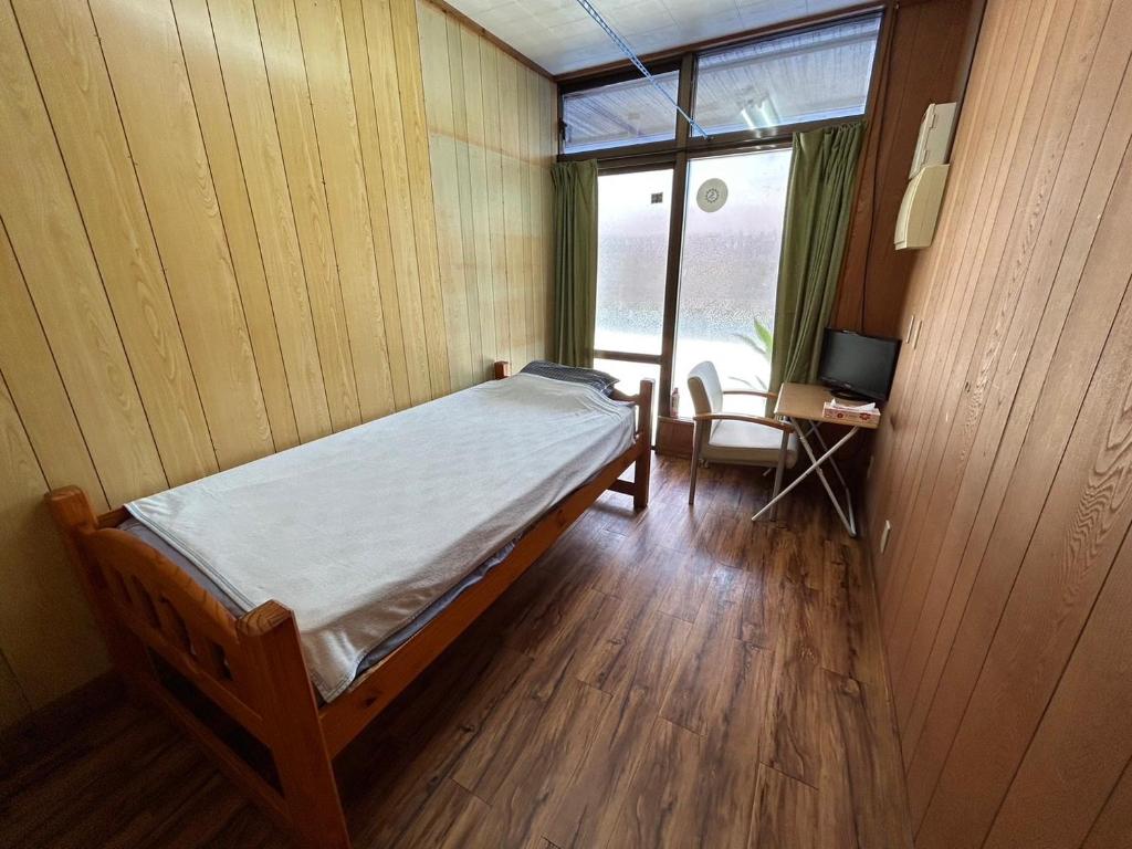 een slaapkamer met een bed en een bureau met een televisie bij 民宿ちねん in Uruma