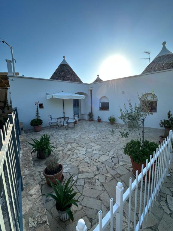 a patio with a white fence and a table and umbrella at Trullo Gnoffa in La Correggia