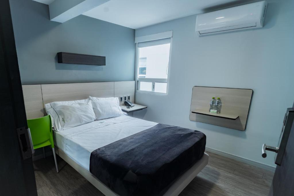 a bedroom with a bed with a blue wall at HOTEL LEMON GREEN -Zona Expo Frente al Centro de Convenciones in Guadalajara