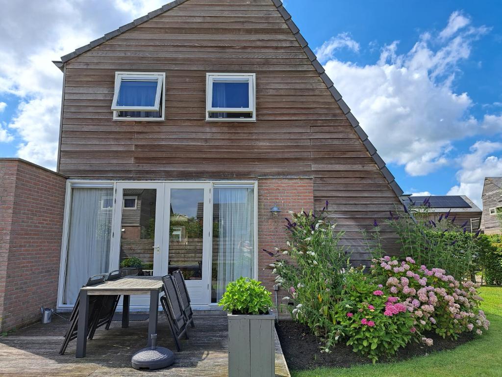 una casa con una mesa y sillas frente a ella en Fries Vakantiehuis, grote tuin, nabij het Pikmeer en Grou