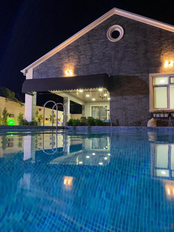 Corat的住宿－Elite Novkhany-Corat Villa，夜间在房子前面的游泳池