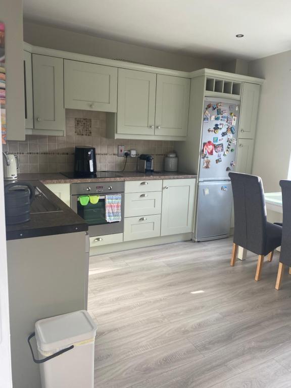 a kitchen with white cabinets and a refrigerator at Cosy home in Dungarvan