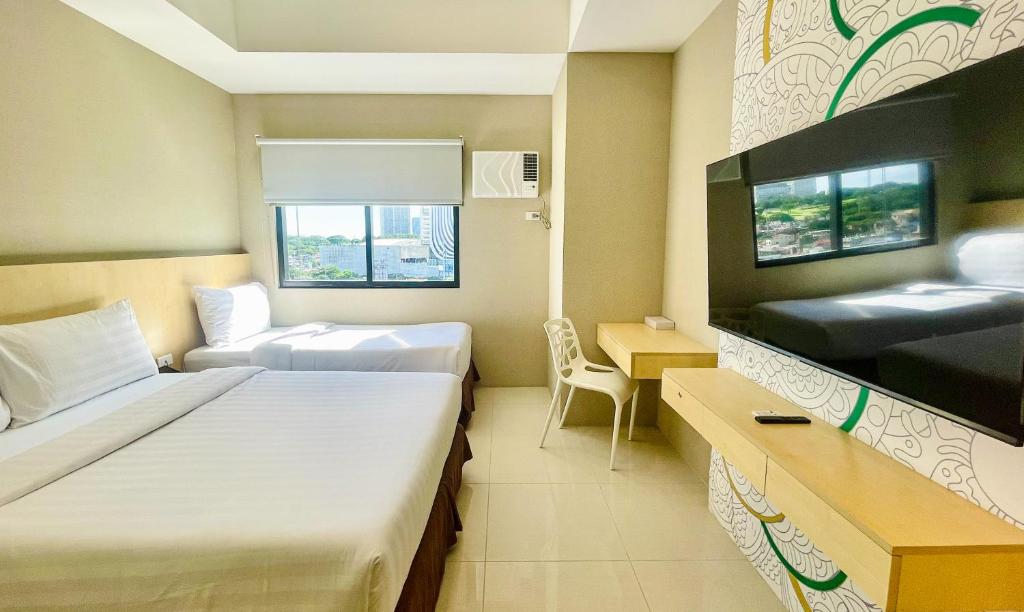a hotel room with two beds and a television at Hotel101 - Fort in Manila