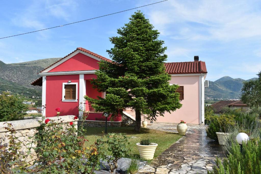 een rood-wit huis met een boom in de tuin bij Rose Garden Villa 