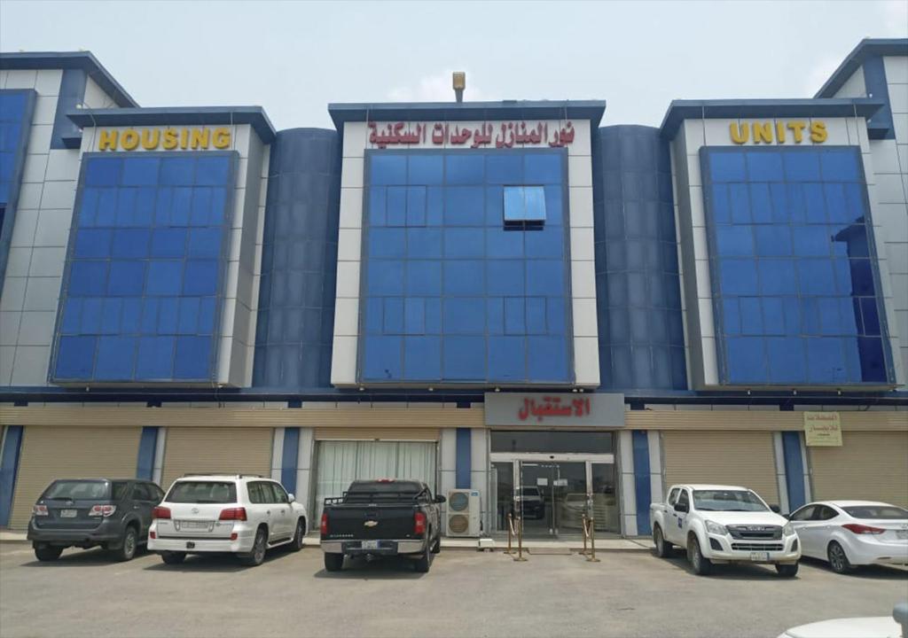 a building with cars parked in a parking lot at نور المنازل للوحدات السكنية in Qarār