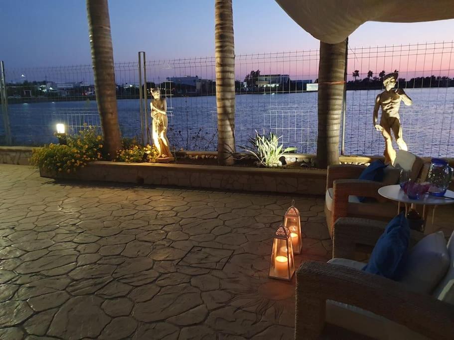 two statues of people standing next to a body of water at Villa Meri in Torre Lapillo