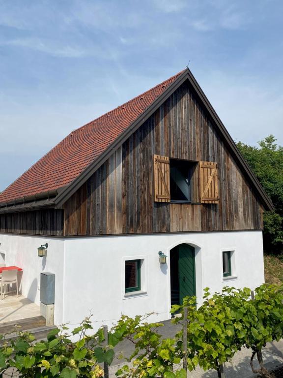 um celeiro com um telhado de madeira e uma porta verde em Weinkeller Röschitz em Roggendorf