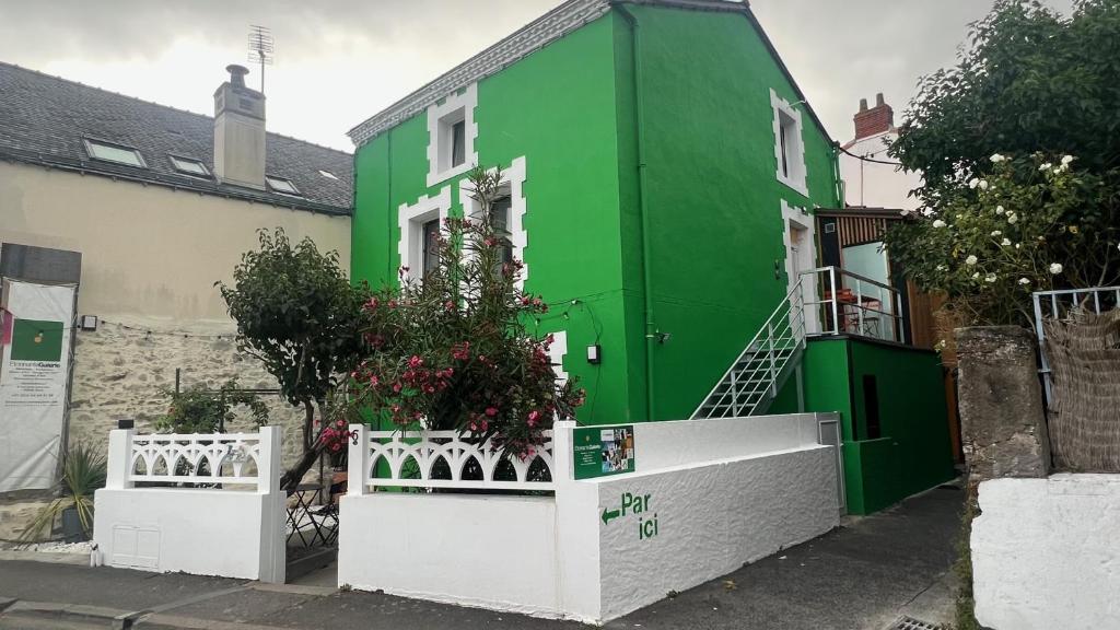 uma casa verde com uma cerca branca em frente em Appartement - Galerie BOTANIC ART Trentemoult em Rezé