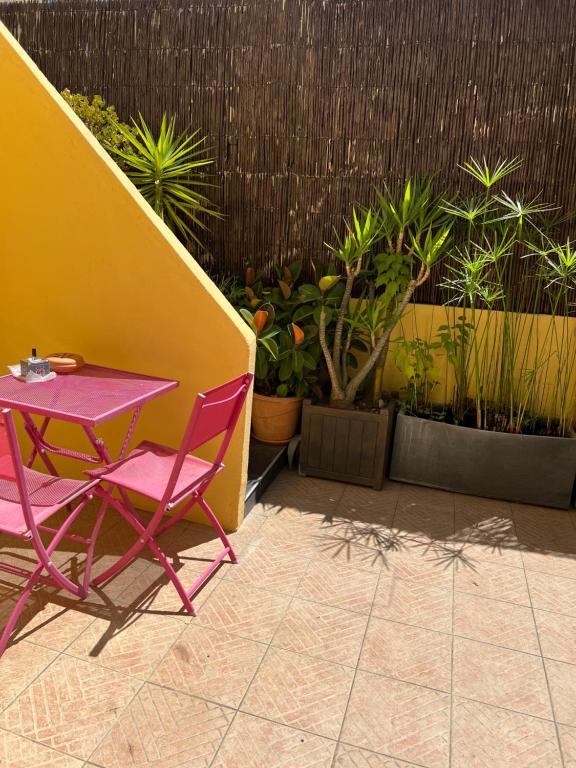 een roze tafel en stoelen op een patio met planten bij Petit nid Catalan , 10 minutes des plages in Perpignan