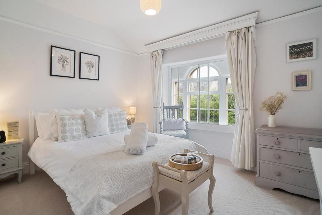 a white bedroom with a large bed and a window at Pearl Cottage in Blockley