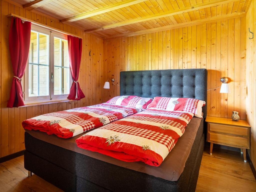 ein großes Bett in einem Zimmer mit Holzwänden in der Unterkunft Chalet am Sunne-Egge auf Axalp bei Brienz in Axalp