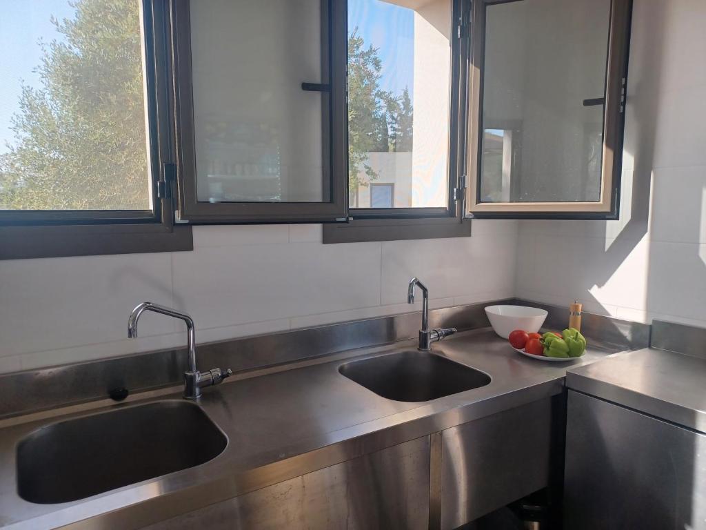 a kitchen with two sinks and two windows at Nirikos Camping in Spasméni Vrísi