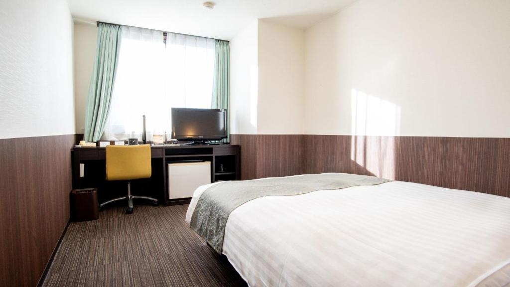 a bedroom with a bed and a desk with a tv at le Lac HOTEL Otsu Ishiyama in Otsu