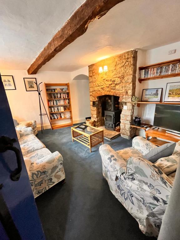 a living room with two couches and a stone fireplace at The Snuggery Cottage in Taunton