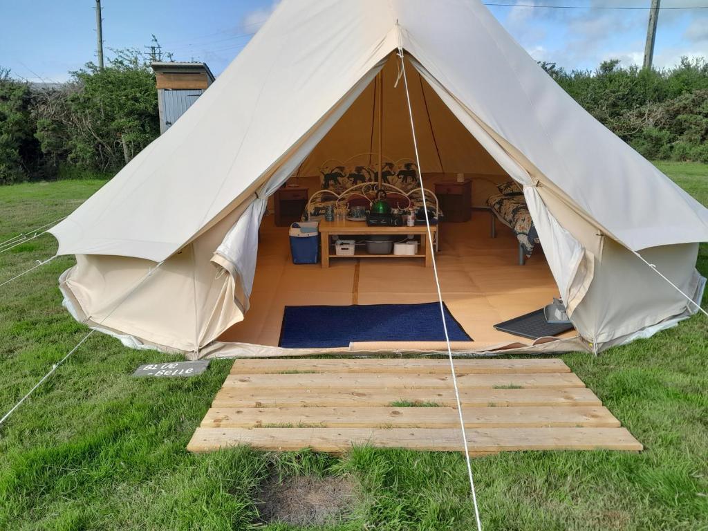 a canvas tent with a wooden floor in a field at Cornish Skies Glamping in Pool