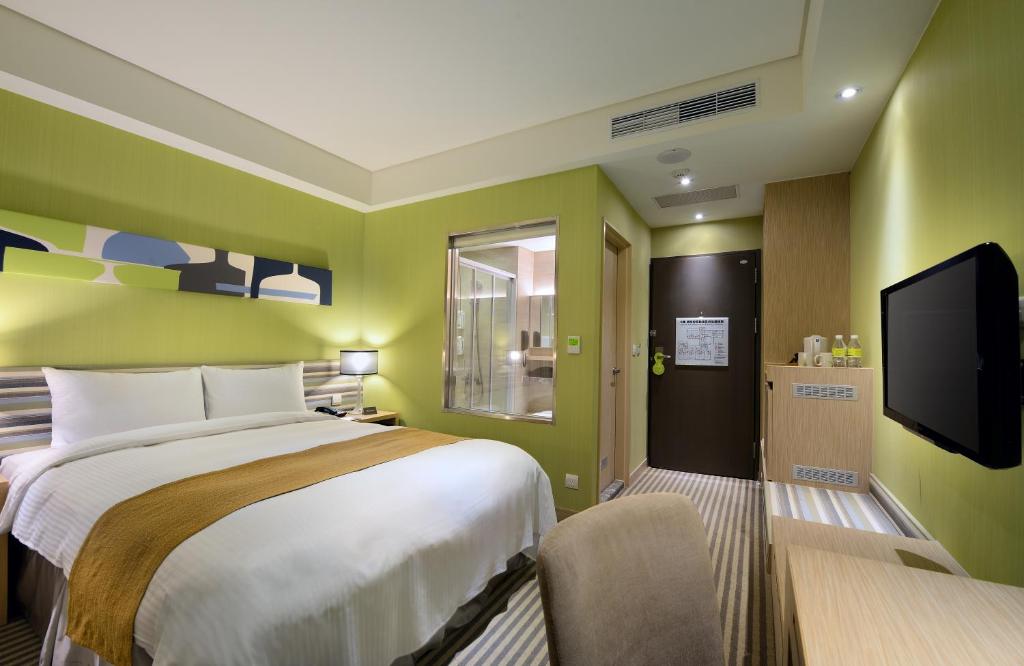a bedroom with a bed and a flat screen tv at Park City Hotel Central Taichung in Taichung