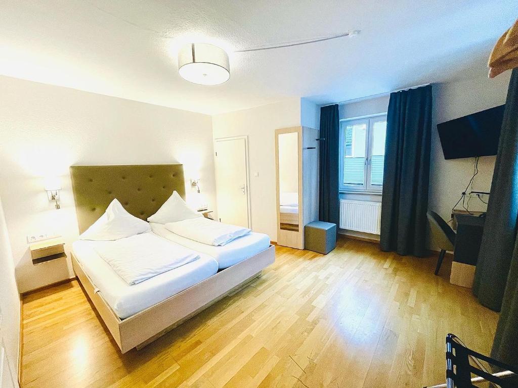 a bedroom with a white bed and a large window at Hotel & Restaurant Fischer in Altenstadt