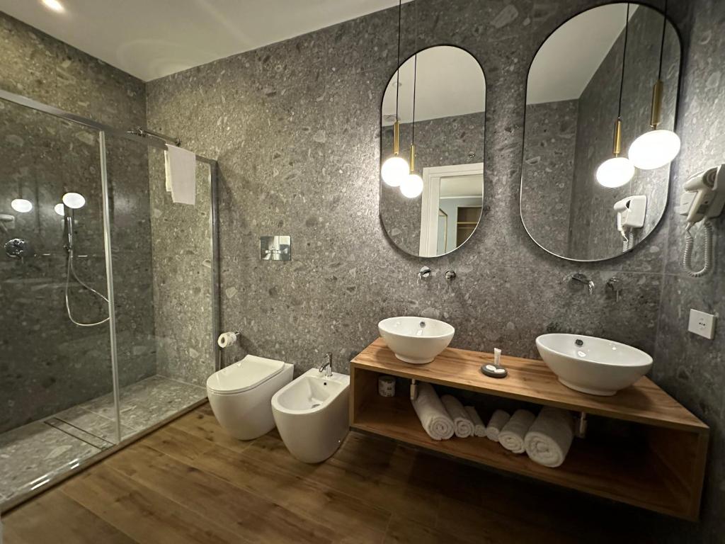 a bathroom with two sinks and a shower and mirrors at Krysos Luxury Rooms in Agrigento