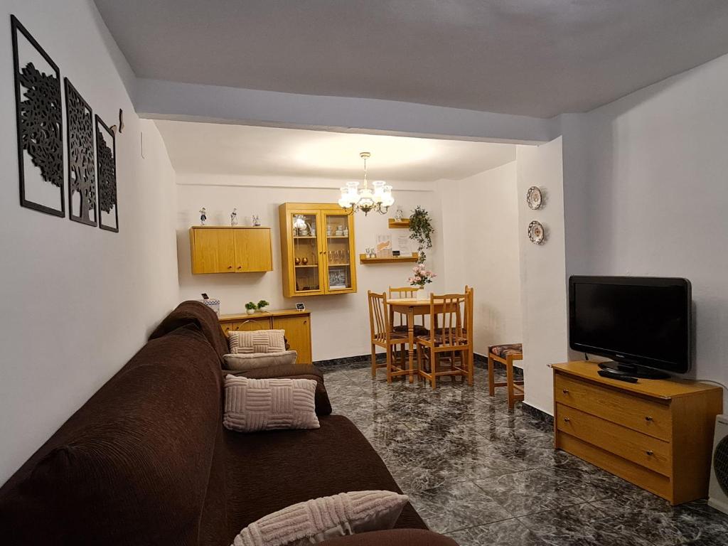 uma sala de estar com um sofá e uma televisão em Casa ' A ca Paca ' em Lanjarón
