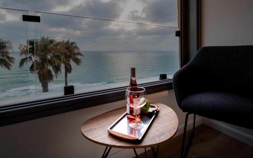 a bottle of wine and a glass on a table next to a window at Beachfront Elegance - Luxe Abode! in Netanya