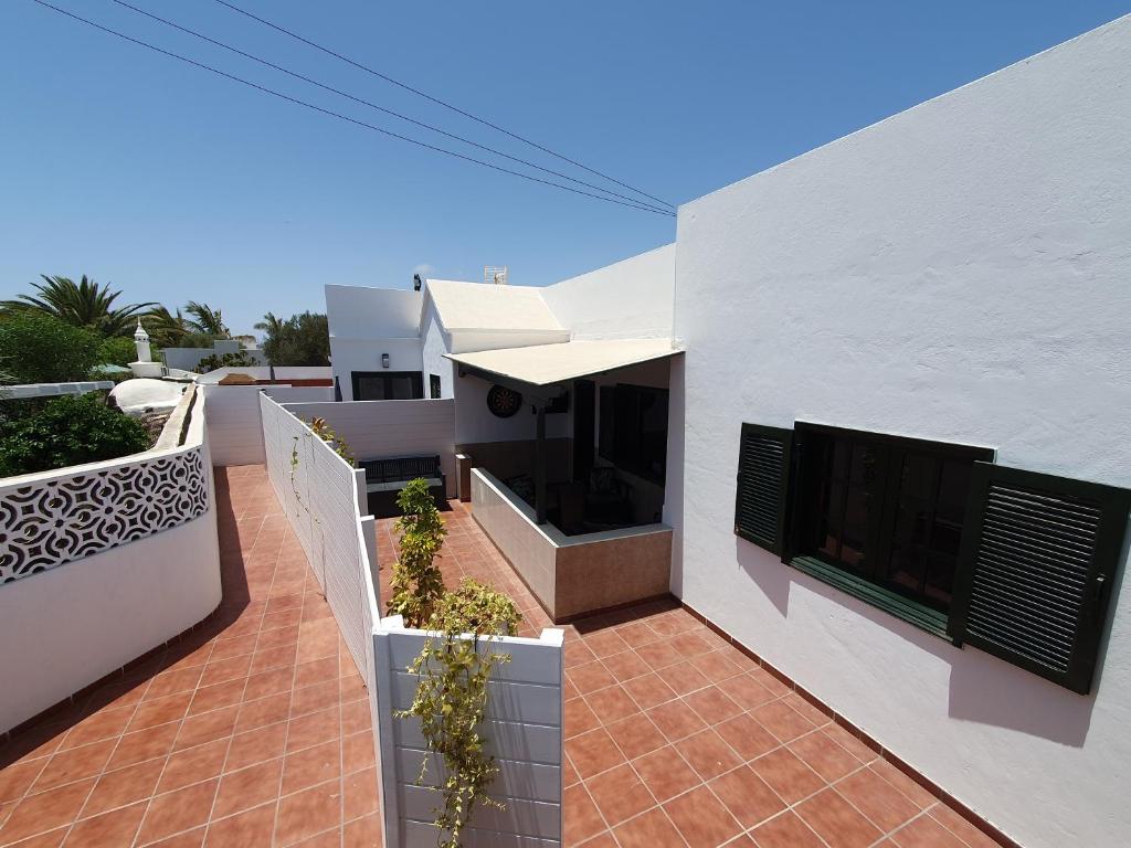 ein weißes Haus mit einer Terrasse mit Topfpflanzen in der Unterkunft Casa El Eco del Volcán 2 in Teguise