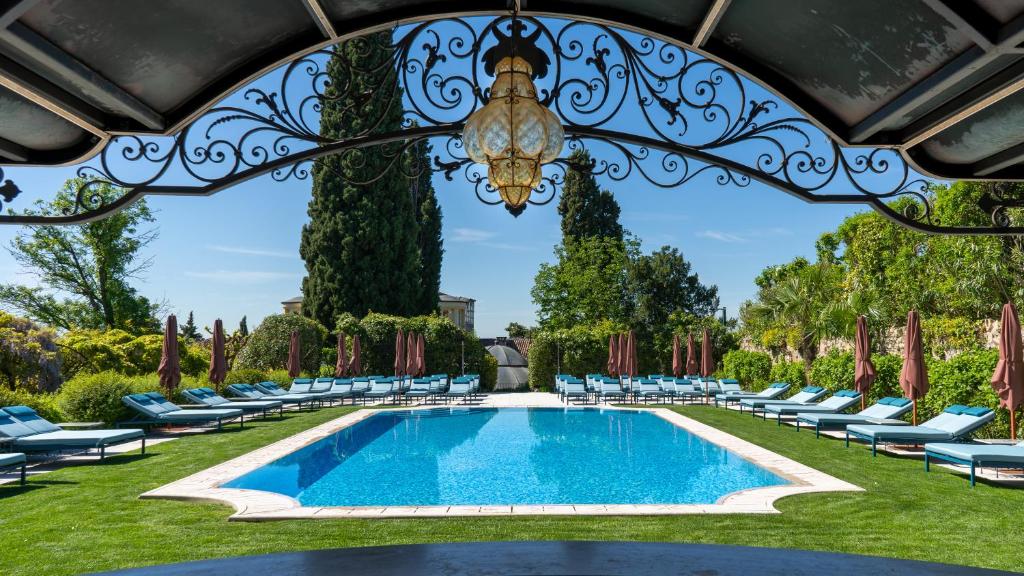 サン・ピエトロ・イン・カリアーノにあるビブロス アート ホテル ヴィラ アミスタのラウンジチェアとシャンデリア付きのプールを併設しています。