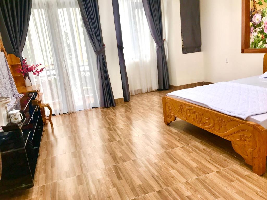 a bedroom with a bed and wooden floors and windows at Hà Linh Motel in Vung Tau
