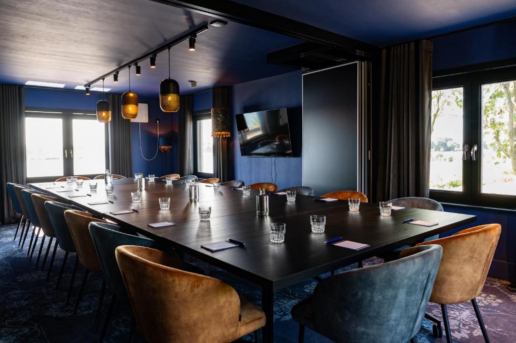 a long table and chairs in a room with blue walls at Boutique Hotel de Bungelaer in Beers