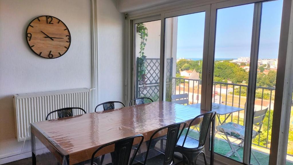 une table à manger avec des chaises et une horloge murale dans l'établissement Grand appartement lumineux vue mer, à La Rochelle