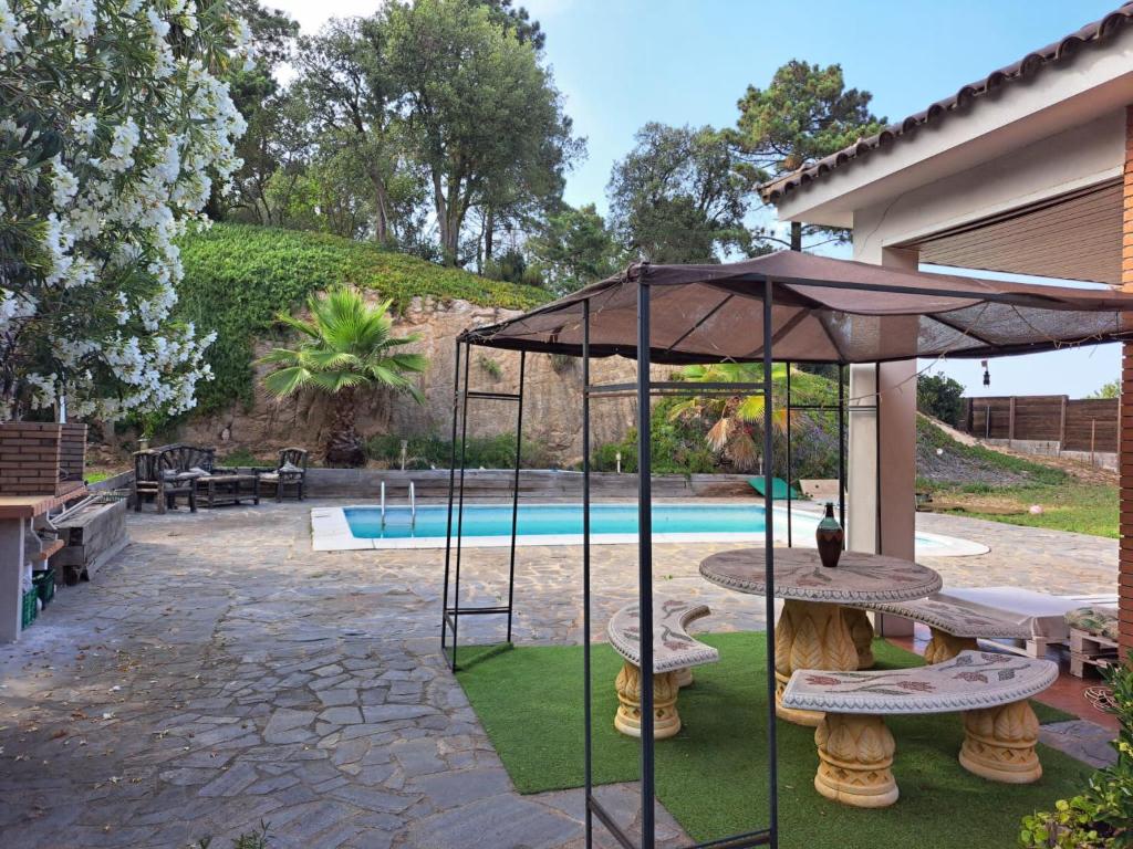 a patio with a table and umbrella and a pool at Villa LLoret Blau in Lloret de Mar