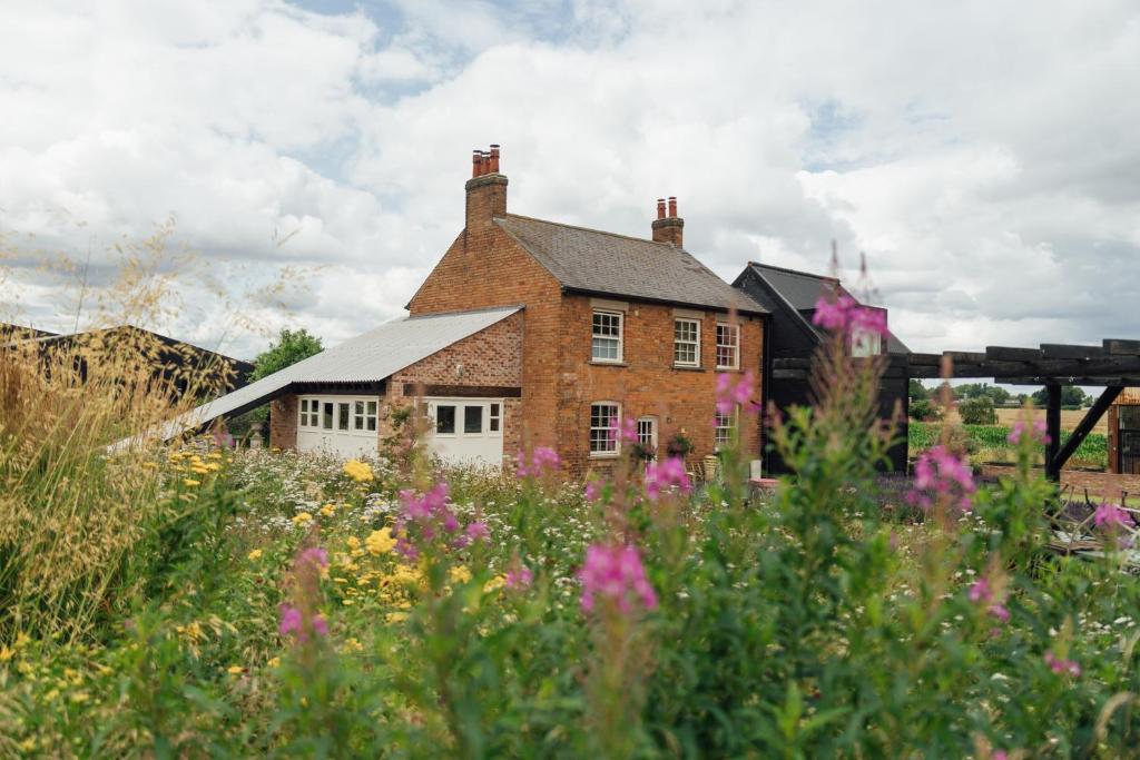 a house in the middle of a field of flowers at Beautiful Countryside Farmhouse in Sutton Bonington