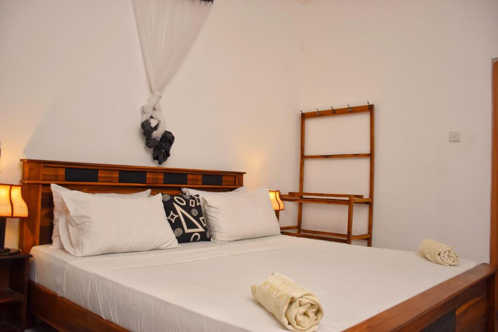a bedroom with a bed with white sheets and pillows at Sunrise Cottage in Sigiriya