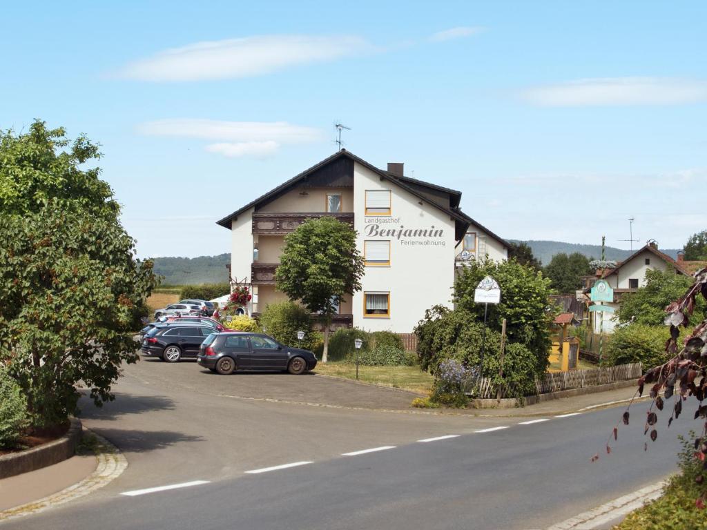 un edificio al lado de una carretera con coches aparcados en Landgasthof Benjamin en Treffelstein