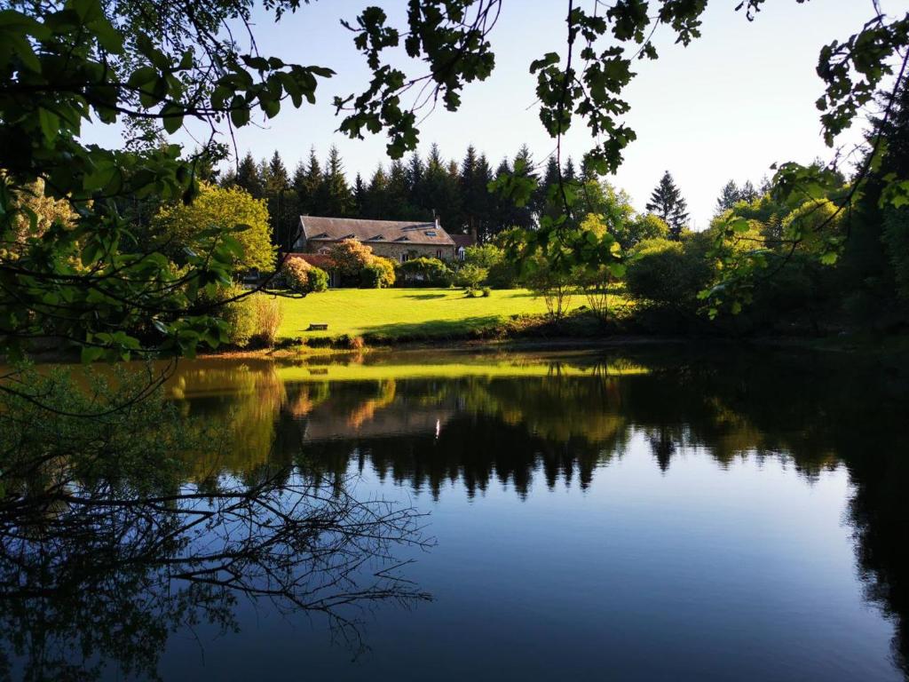 a house sitting on a hill next to a lake at DOMAINE DES CAPUCINS in Bussière-Saint-Georges