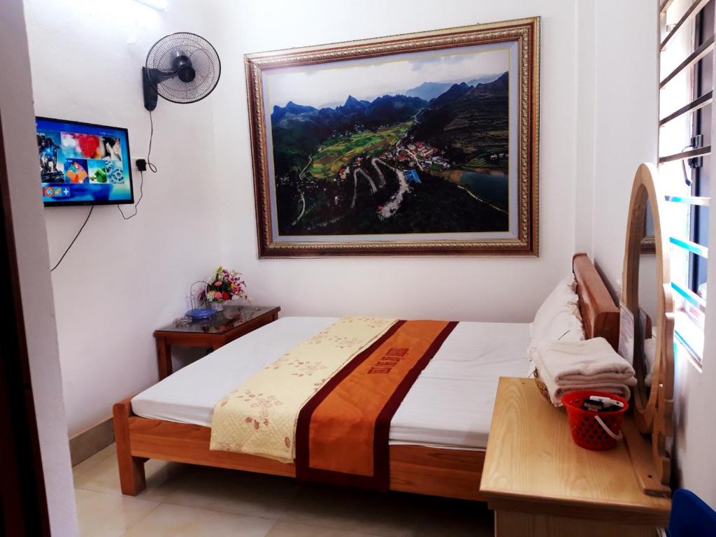 1 dormitorio con 1 cama con una pintura en la pared en Thien An Guest House, en Yên Minh
