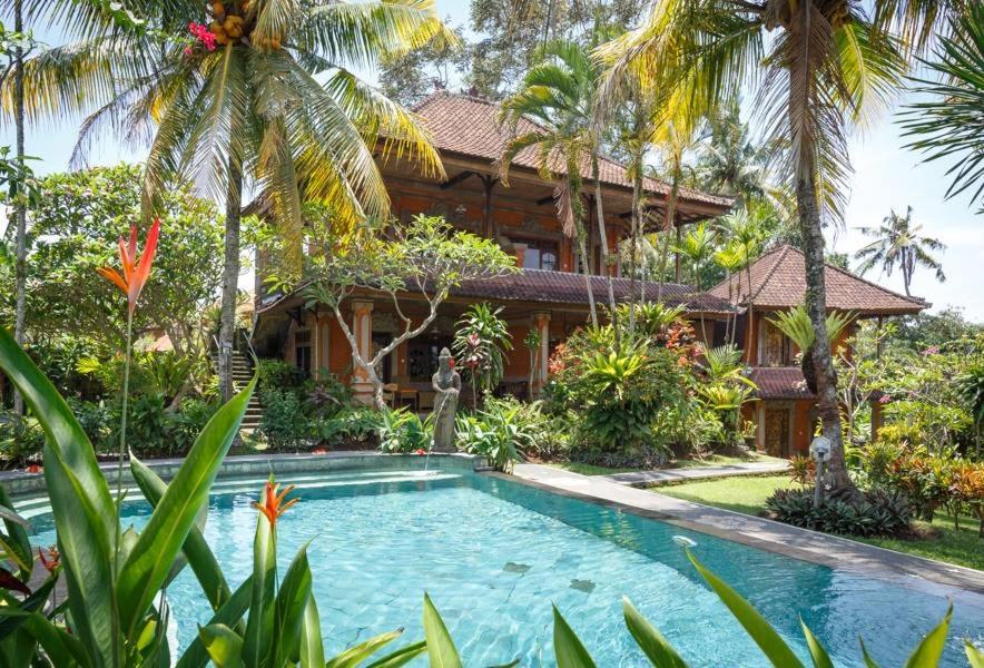 a resort with a swimming pool in front of a house at White House in Ubud