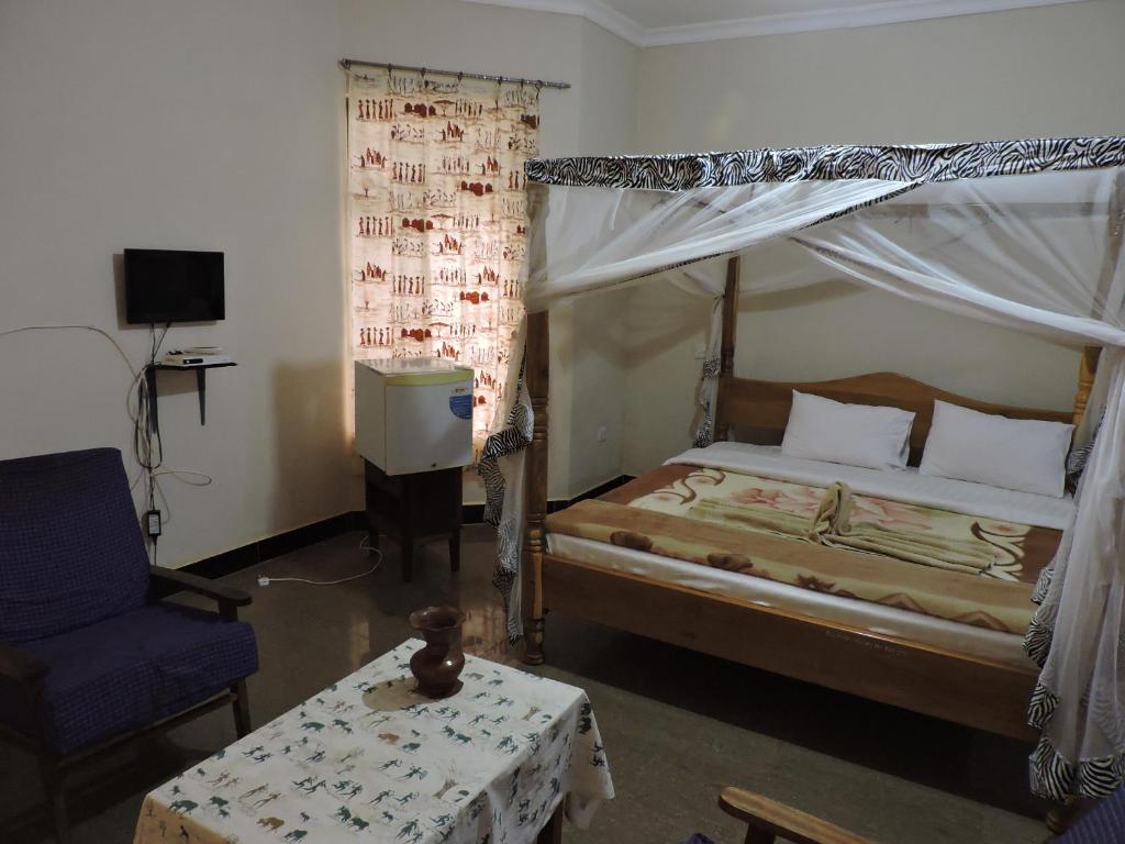 een slaapkamer met een bed, een stoel en een tafel bij Perigrin Rest House in Karatu