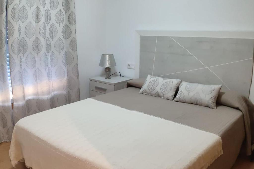 a bedroom with a white bed with a white headboard at A RIA DE PONTEVEDRA in Pontevedra