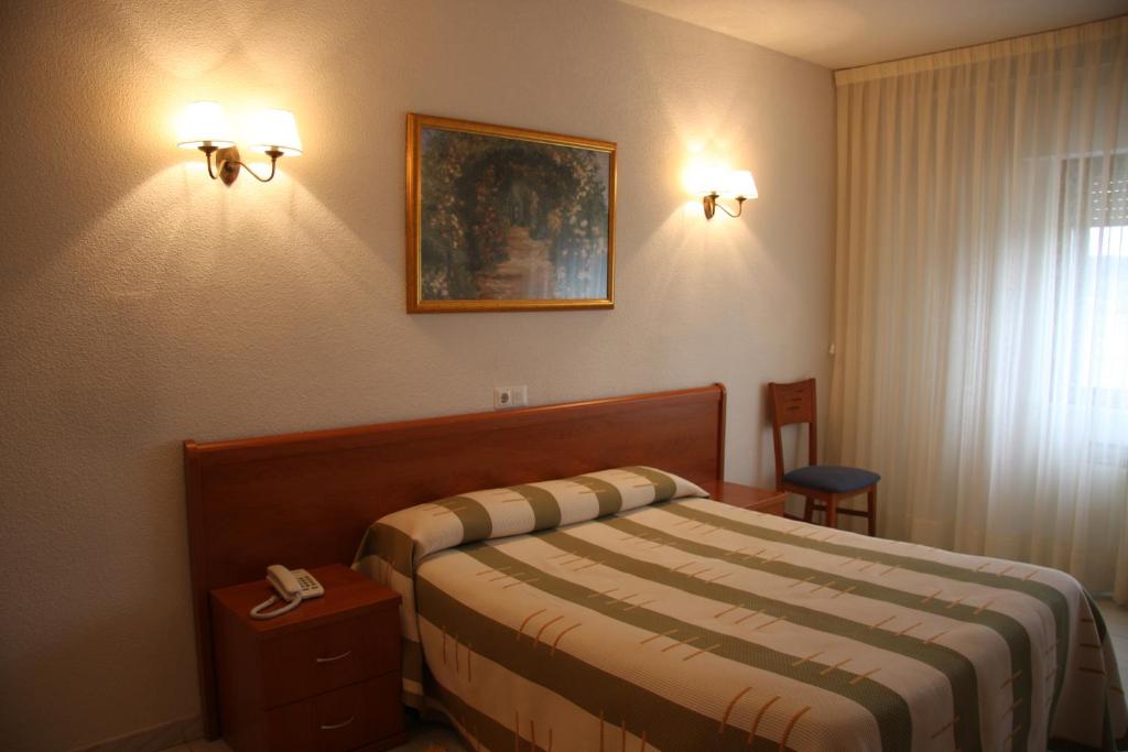 une chambre d'hôtel avec un lit et une photo sur le mur dans l'établissement Hotel Alameda, à Alba de Tormes