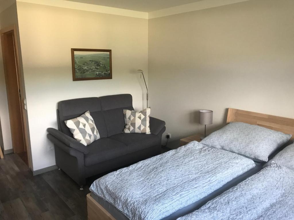 a bedroom with a bed and a couch and a chair at Im alten Büro in Kelberg