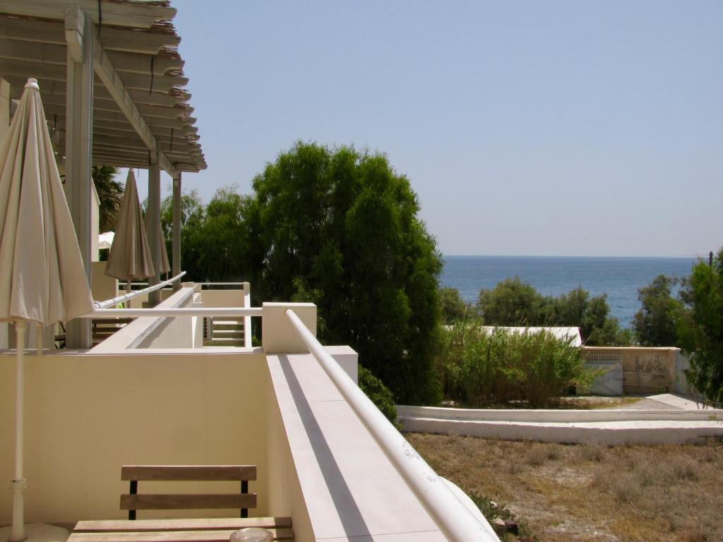 ein Gebäude mit einer Bank und Sonnenschirmen und dem Meer in der Unterkunft Sail Inn Studios & Apartments in Kamari