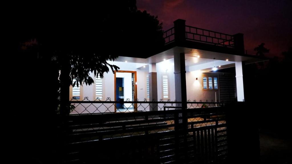ein nachts beleuchtetes Haus mit einem Zaun in der Unterkunft WAYANAD OASIS VILLa in Kalpatta