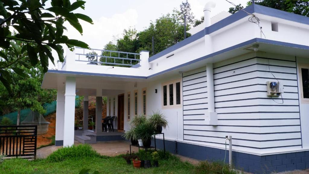 a white house with a blue roof at WAYANAD OASIS VILLa in Kalpetta
